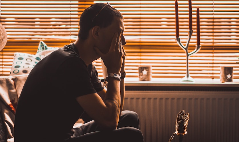 man sitting on chair covering his eyes