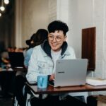 smiling man sitting and using Samsung laptop near people