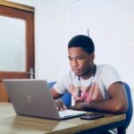 man in grey shirt using grey laptop computer