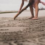 a woman digging in the sand with a stick