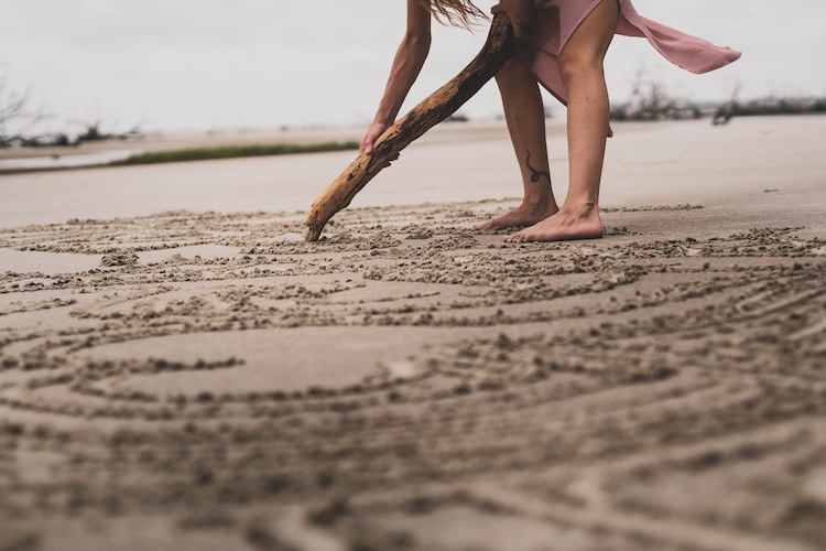 a woman digging in the sand with a stick