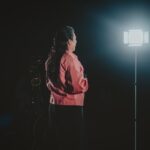 a woman standing in front of a light in the dark