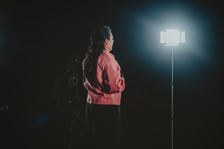 a woman standing in front of a light in the dark