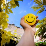 a hand holding a yellow smiley face ball