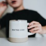 woman in black shirt holding white ceramic mug